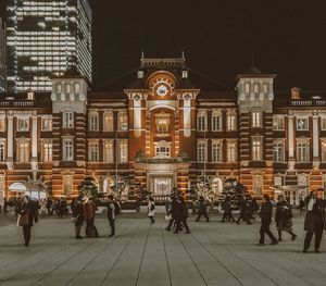 People on street against buildings at night