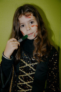 Portrait of a girl with halloween makeup drinking liquid from a syringe.