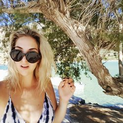 Portrait of young woman holding sunglasses