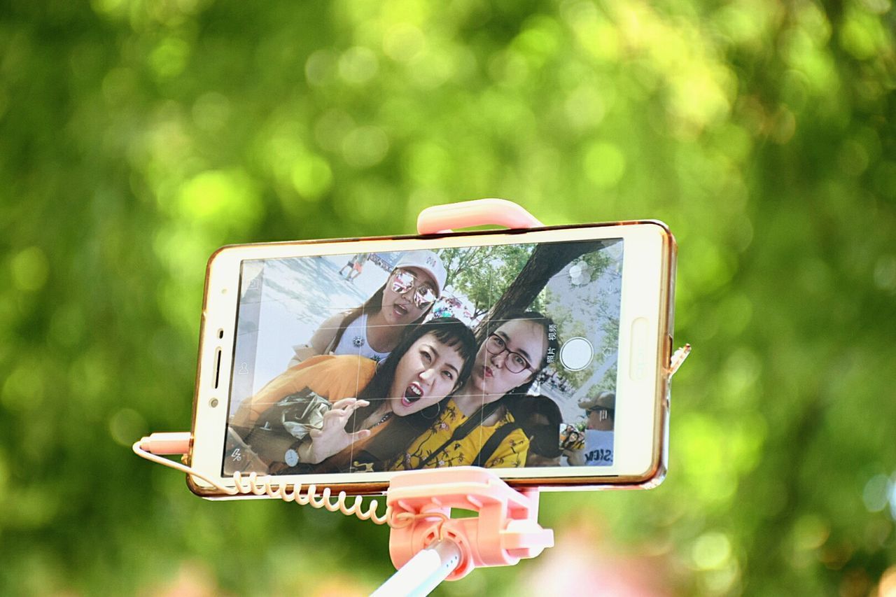 PORTRAIT OF A SMILING YOUNG WOMAN WITH CAMERA