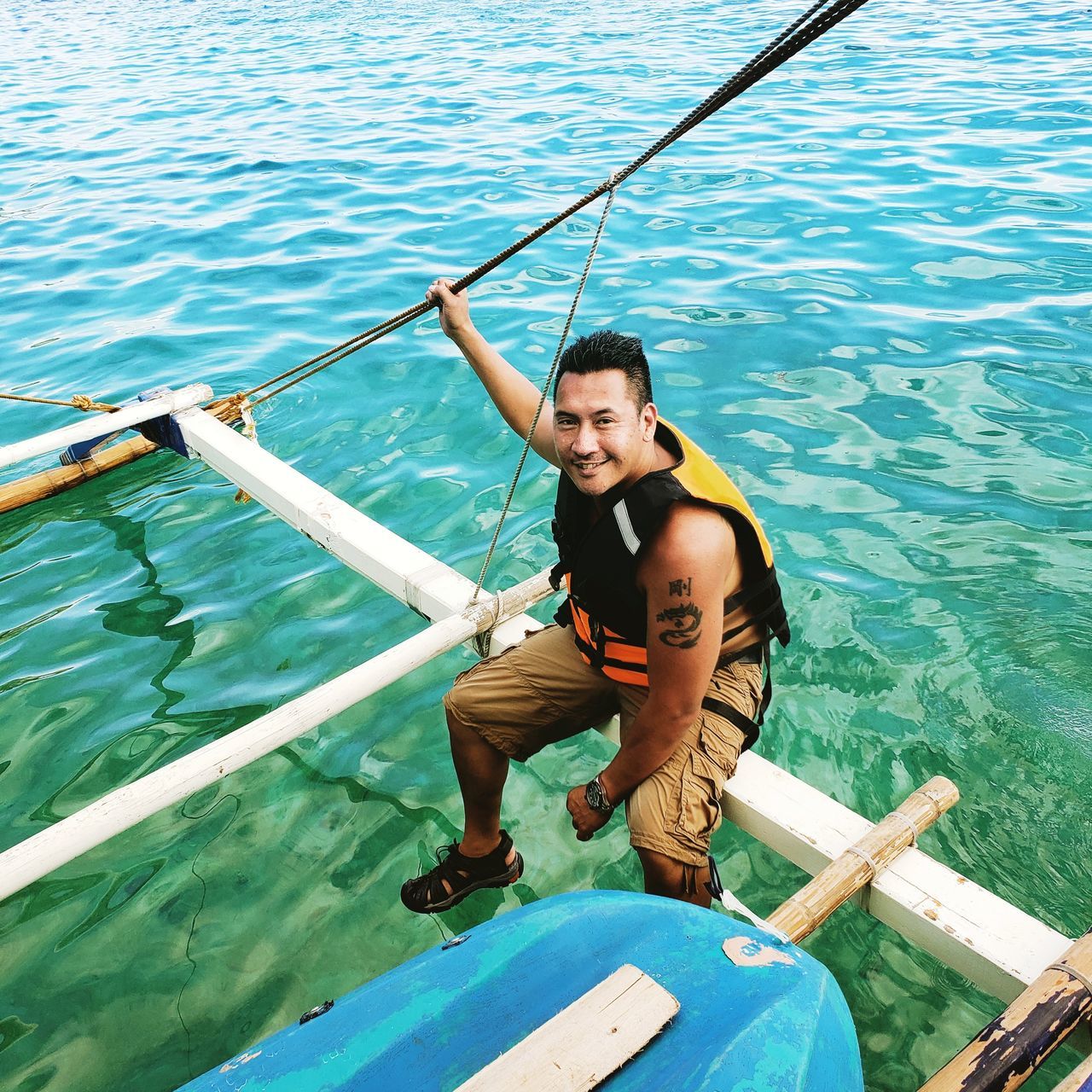 water, nautical vessel, real people, leisure activity, transportation, one person, nature, lifestyles, sea, mode of transportation, day, casual clothing, young men, holding, high angle view, young adult, men, front view, looking at camera, outdoors, rowing