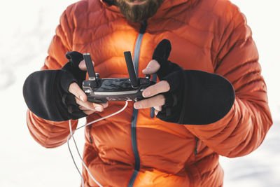 Man using remote control while standing on snow covered field