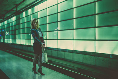 Full length portrait of woman standing in corridor