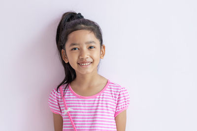 Portrait of a smiling girl standing against white background