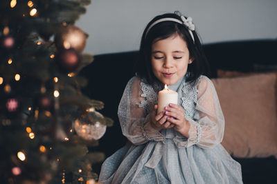 Cute girl holding candle sitting on chair