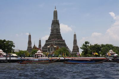 Boats moored in chao phraya river at wat arun against sky