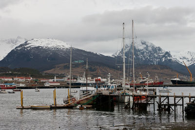 Sailboats moored on river by mountain against sky