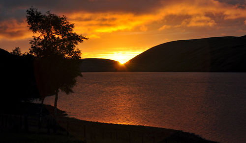 Scenic view of lake against orange sky