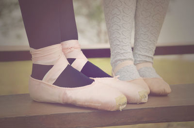 Low section of woman and girl wearing ballet shoes