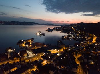 High angle view of illuminated city buildings against sky at sunset