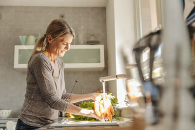 Woman in kitchen washing carrots