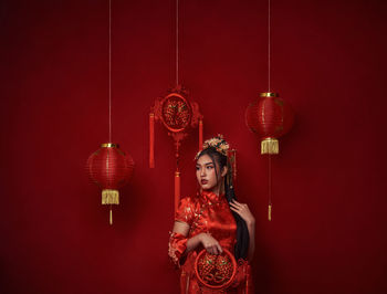 Woman holding lantern hanging against wall
