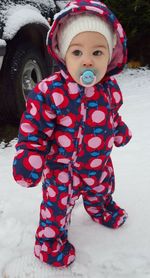 Full length of baby in warm clothing standing on snow covered field