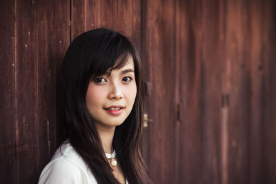 Portrait of young woman against wooden wall