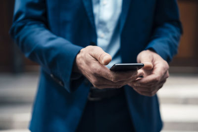 Businessman text messaging through smart phone