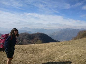 Woman with backpack standing on mountain against sky