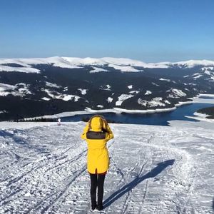 Rear view of woman standing on snowcapped mountain