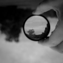 Close-up of hand holding sunglasses against sky