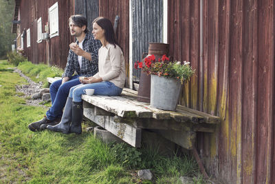 Couple having breakfast while sitting outside barn at farm