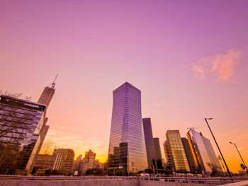 Modern buildings in city against sky during sunset