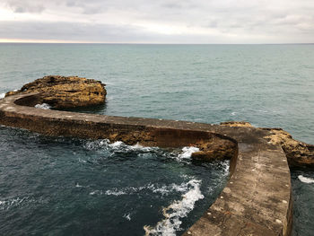 Scenic view of rocks in sea against sky