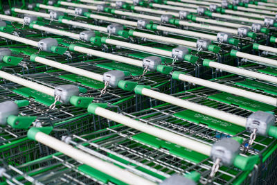 Many empty green shopping carts in row. row of parked trolleys in supermarket.