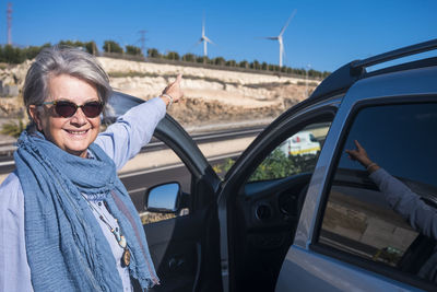 Portrait of woman wearing sunglasses by car