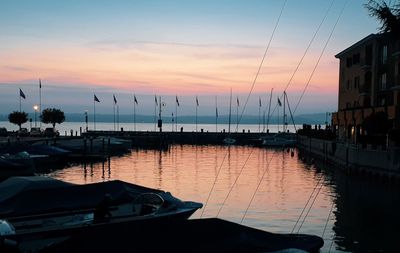 Boats moored at harbor during sunset