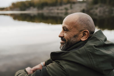 Smiling male hiker looking away by lake during vacation