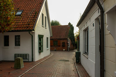 Alley amidst houses in town against sky