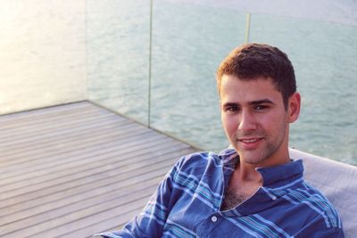 Portrait of young man sitting against sea