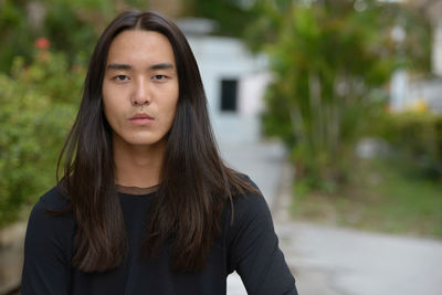 Portrait of man with long hair standing outdoors