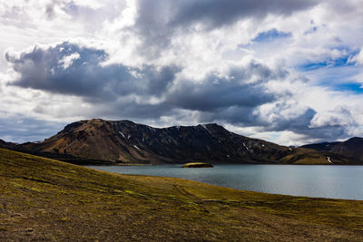 Scenic view of lake by mountains against sky