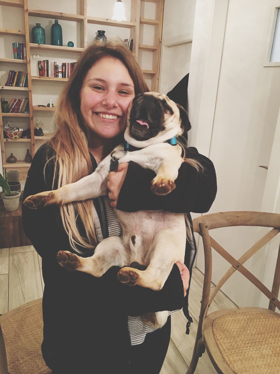 person, portrait, looking at camera, lifestyles, sitting, casual clothing, indoors, young adult, leisure activity, domestic animals, smiling, full length, front view, togetherness, mammal, pets, three quarter length, young women