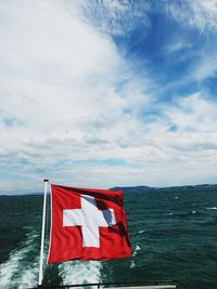 Red flag on sea against sky