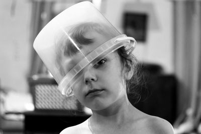 Close-up portrait of cute boy with bucket on head at home