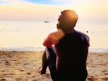 Rear view of man on beach against sky during sunset