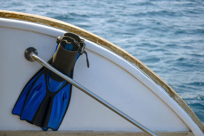 Fins for swimming are inserted behind yacht's handrail. view on the background of blue sea.