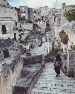 Rear view of woman walking on steps in city