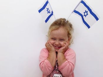 Close-up of cheerful girl with israeli flag against white background