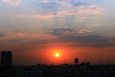 Silhouette of city against cloudy sky during sunset