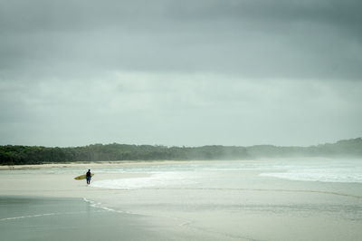 Side view of male surfer standing on beach