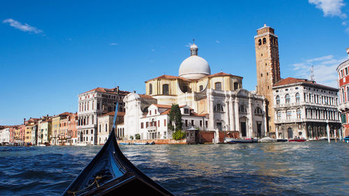 Gondola on canal by buildings against sky