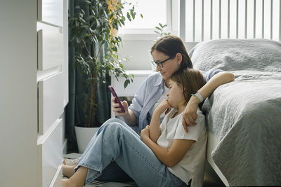 Young woman using mobile phone while sitting on sofa at home