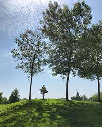 Man standing by tree on field against sky