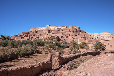 Ancient fortress and residential structures on hill against blue sky