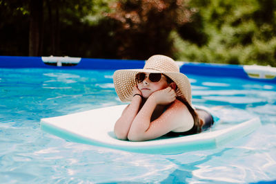 Girl lying on pool raft in swimming pool