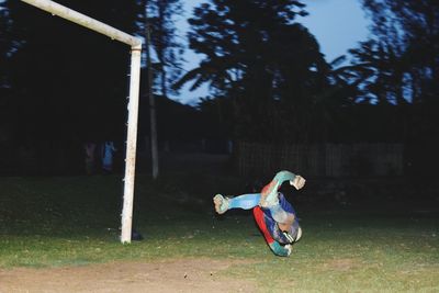 Full length of man playing soccer on field at dusk