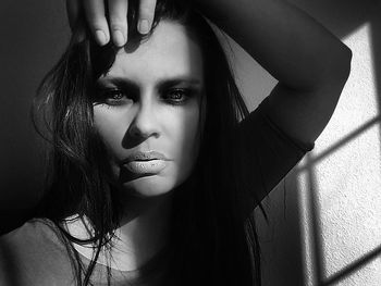 Portrait of young woman with hand in hair against wall at home