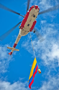 Low angle view helicopter hovering against cloudy sky